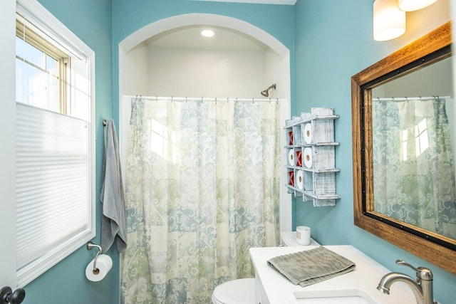 bathroom with a shower with shower curtain, a sink, and toilet