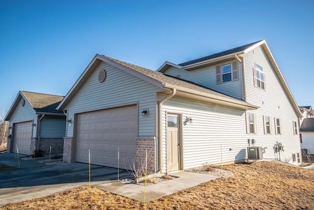 view of property exterior with a garage and central AC