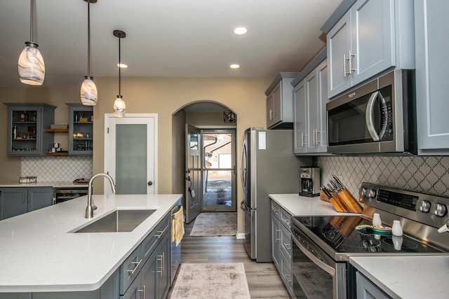 kitchen with light countertops, appliances with stainless steel finishes, hanging light fixtures, and a sink