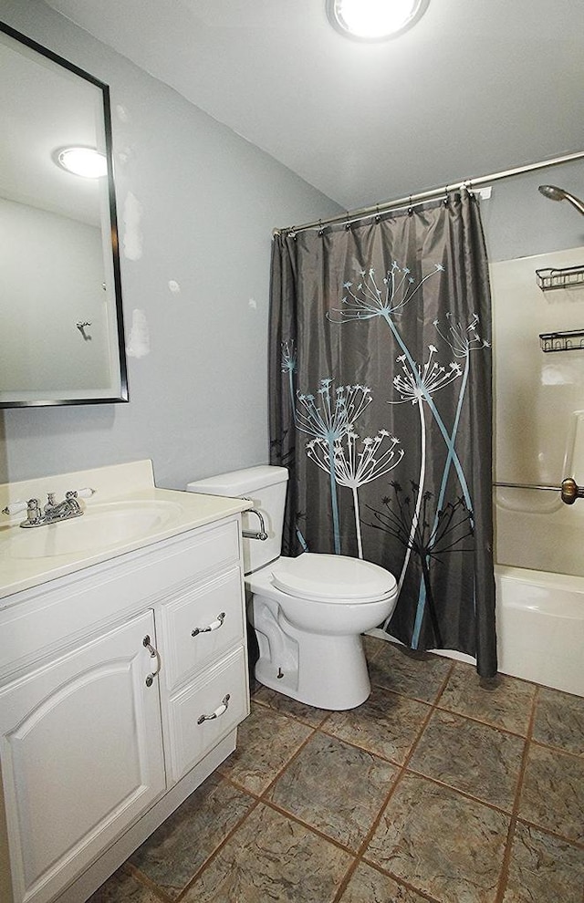 full bathroom featuring stone finish flooring, shower / bath combo with shower curtain, vanity, and toilet