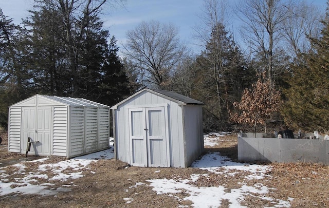 snow covered structure featuring a shed, fence, and an outdoor structure