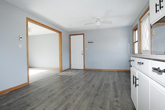 empty room featuring a ceiling fan, baseboards, and wood finished floors