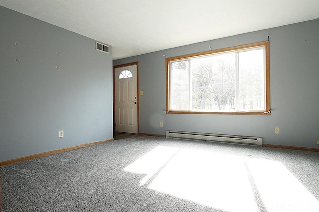 empty room with a baseboard heating unit, visible vents, carpet floors, and baseboards