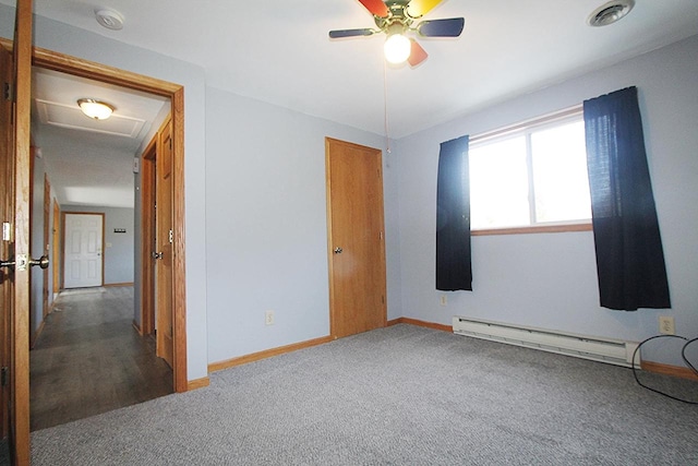 carpeted spare room featuring a baseboard radiator, visible vents, attic access, a ceiling fan, and baseboards