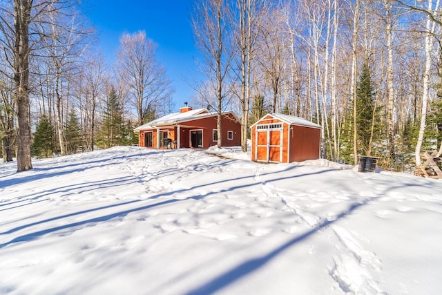 yard covered in snow with a garage, an outbuilding, and a storage unit