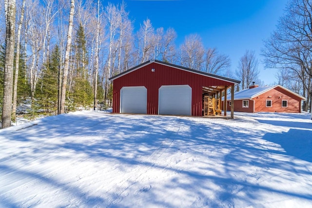 snow covered garage with a garage and driveway