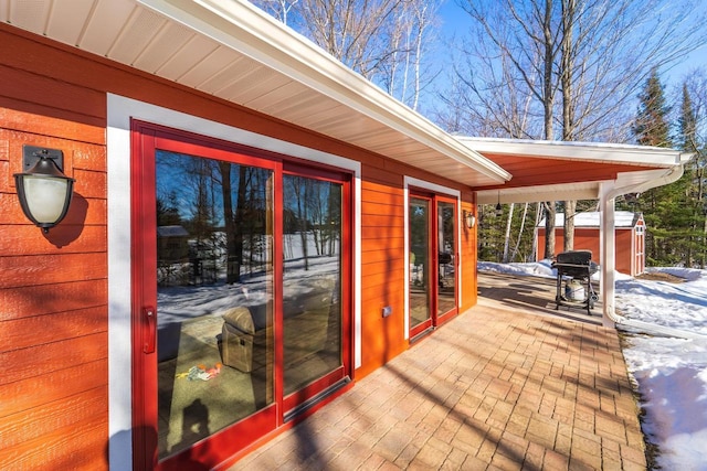 snow covered deck with area for grilling and a patio area