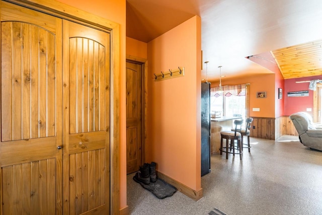 hall featuring a wainscoted wall and wooden walls