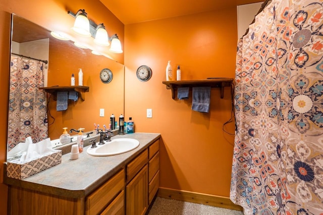 bathroom with curtained shower, vanity, and baseboards