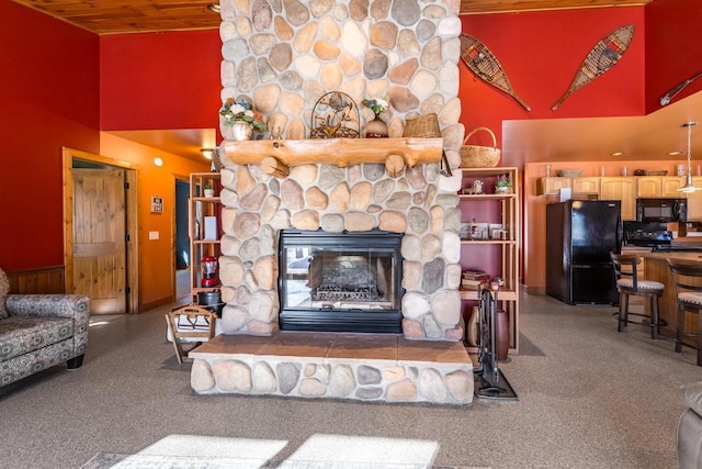 living area with a high ceiling and a stone fireplace