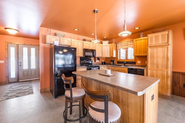 kitchen featuring a kitchen breakfast bar, a center island, black appliances, pendant lighting, and a sink