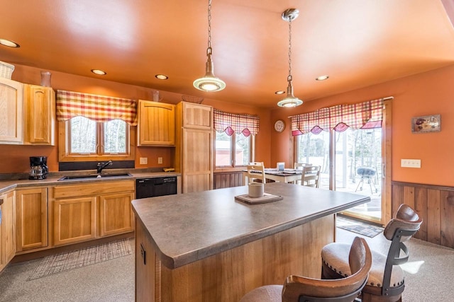 kitchen with a center island, hanging light fixtures, wainscoting, a sink, and dishwasher