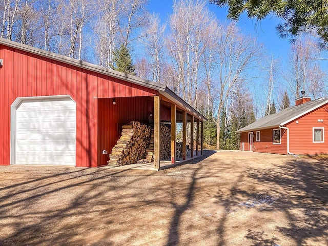 exterior space with driveway, a detached garage, and an outbuilding