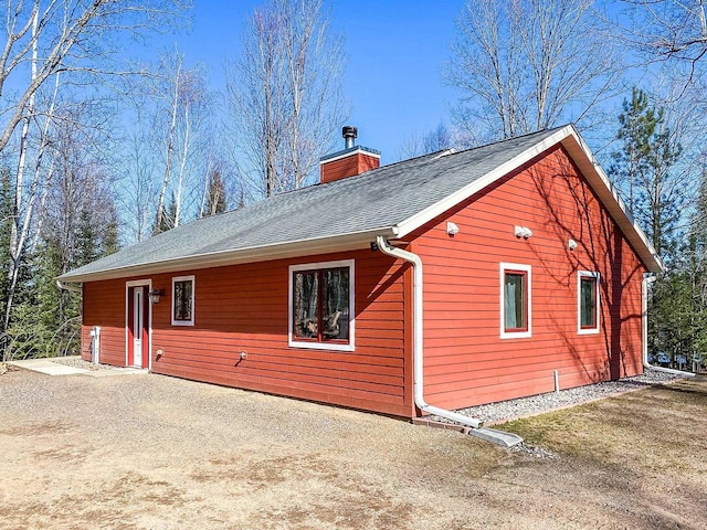 view of property exterior with roof with shingles and a chimney