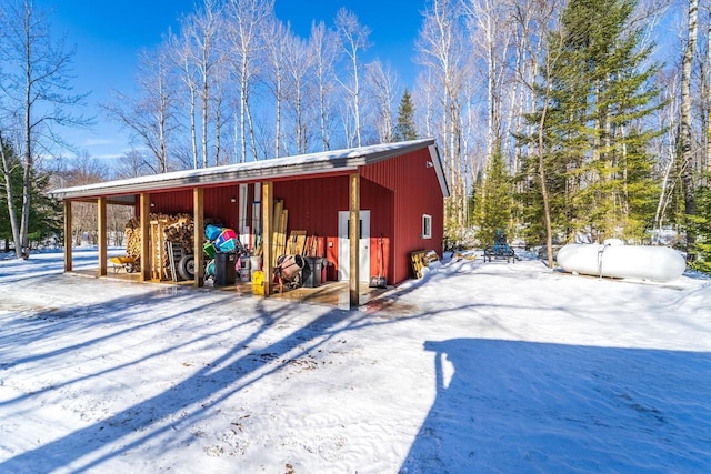 snow covered structure with an outbuilding and an outdoor structure