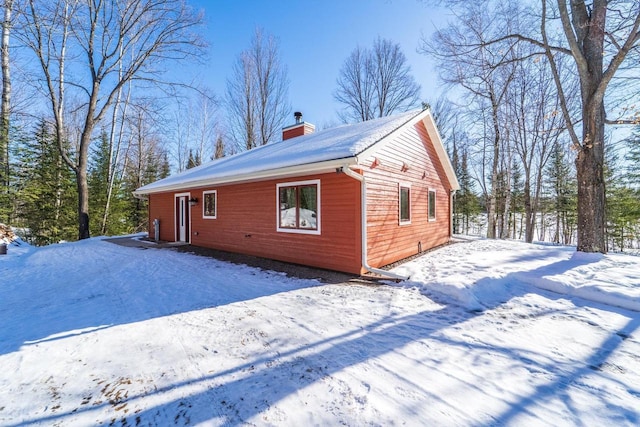 view of snow covered exterior with a chimney