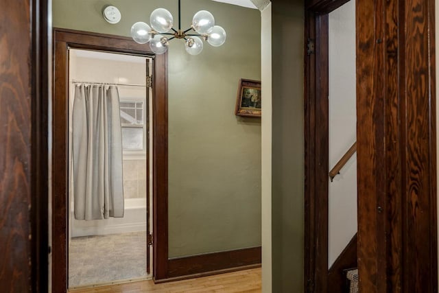 hall with wood finished floors and an inviting chandelier