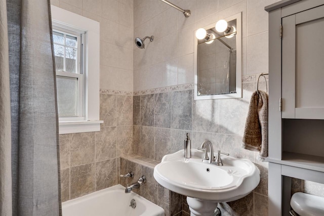 full bathroom with a sink, washtub / shower combination, and tile walls