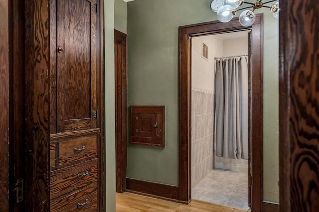 hallway with a notable chandelier and wood finished floors