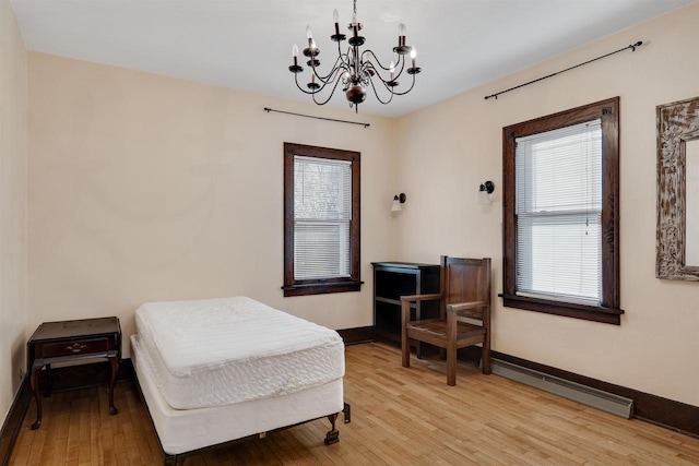 bedroom with light wood finished floors, baseboards, and a notable chandelier