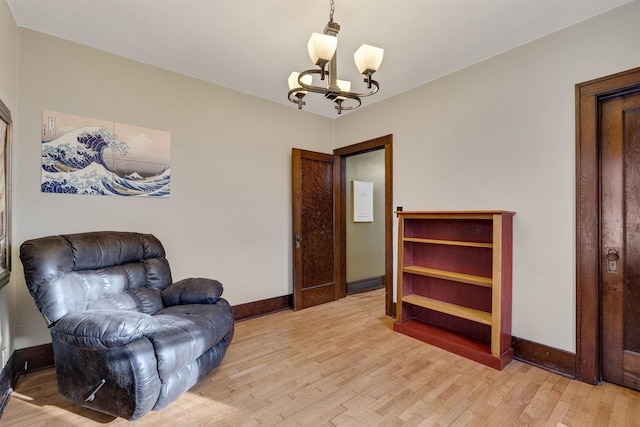 sitting room featuring baseboards, light wood-type flooring, and an inviting chandelier