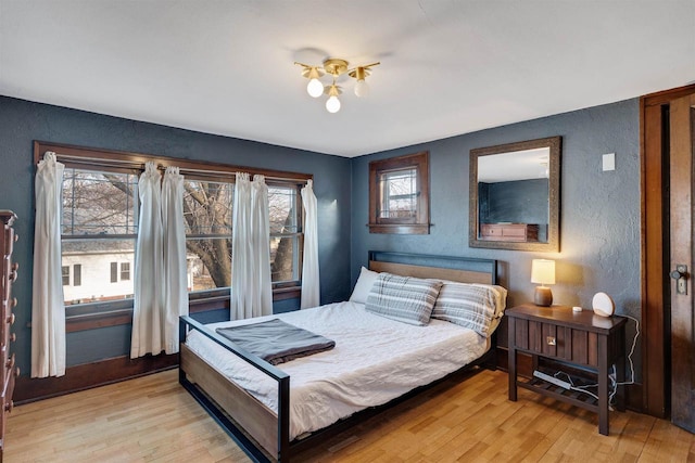 bedroom with light wood finished floors and a textured wall