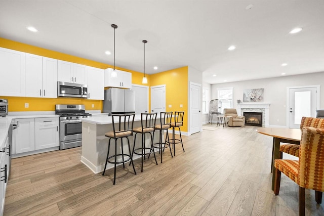 kitchen featuring appliances with stainless steel finishes, a center island, open floor plan, and light wood-style flooring