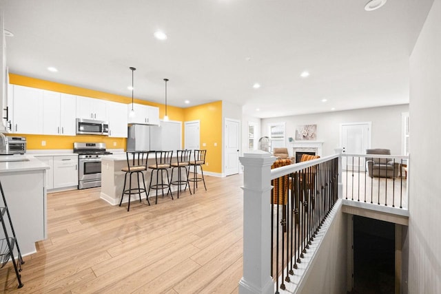 kitchen featuring a center island, light wood-style flooring, appliances with stainless steel finishes, open floor plan, and a kitchen breakfast bar