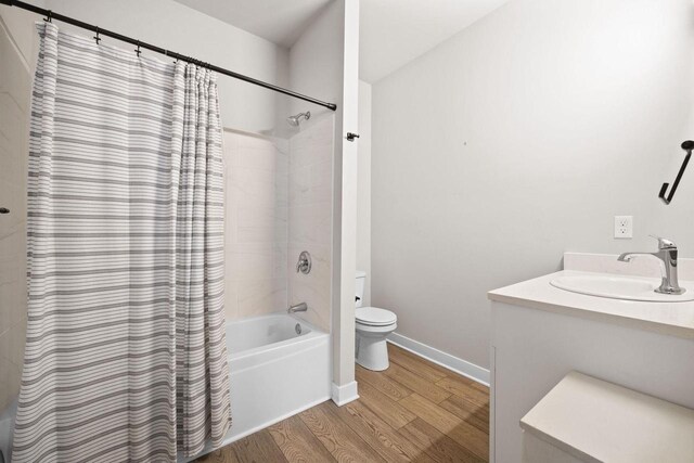 full bathroom with toilet, wood finished floors, vanity, baseboards, and shower / bathtub combination with curtain