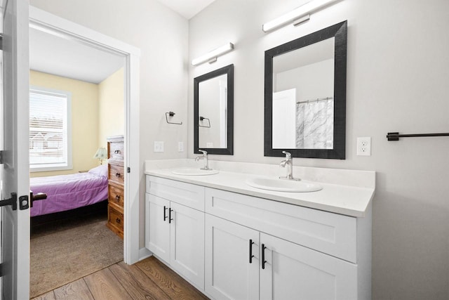 full bath with ensuite bathroom, double vanity, wood finished floors, and a sink