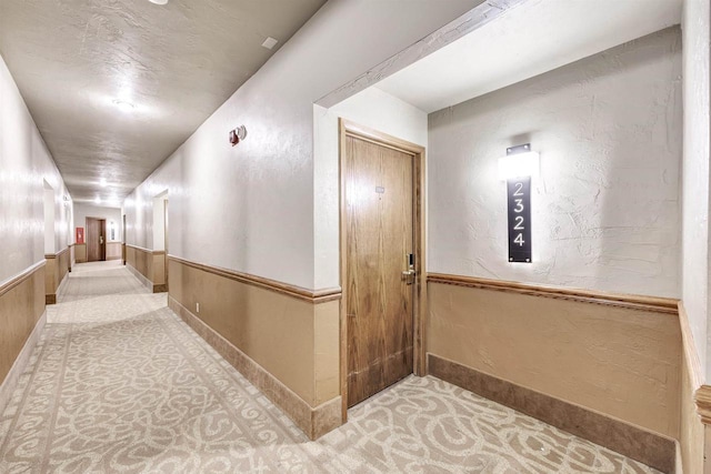 corridor featuring a wainscoted wall and a textured wall