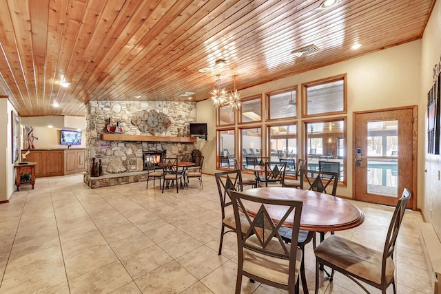 dining area featuring light tile patterned floors, a fireplace, wood ceiling, and a notable chandelier