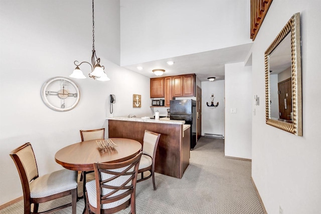 dining area with light carpet, a chandelier, a towering ceiling, and baseboards