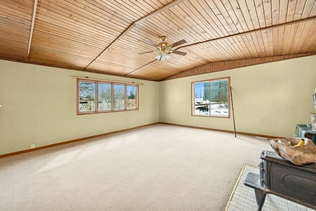 interior space with lofted ceiling, light colored carpet, wood ceiling, a wood stove, and baseboards