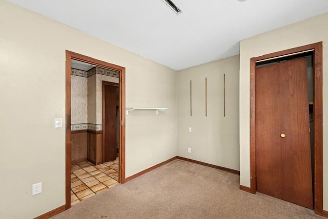 unfurnished bedroom featuring light carpet, baseboards, and a closet