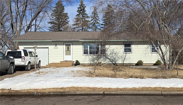 single story home with an attached garage and roof with shingles