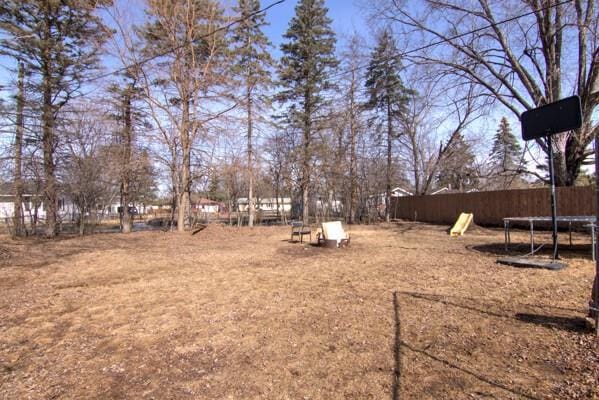 view of yard featuring a trampoline and fence