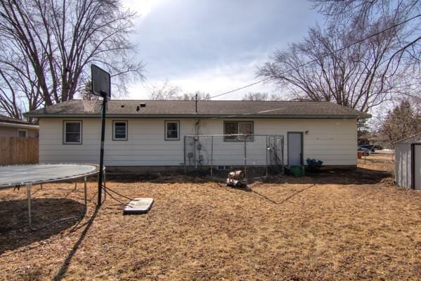 rear view of property featuring a trampoline and fence