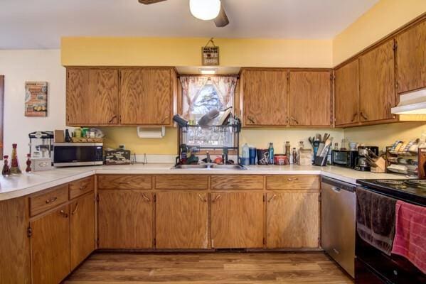 kitchen featuring a sink, stainless steel appliances, light countertops, light wood-style floors, and under cabinet range hood