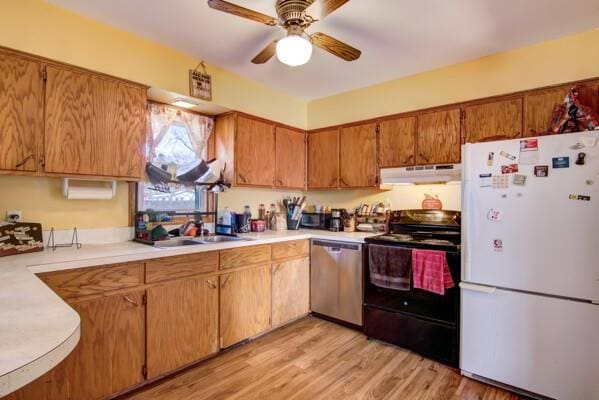 kitchen with black / electric stove, freestanding refrigerator, light countertops, under cabinet range hood, and stainless steel dishwasher