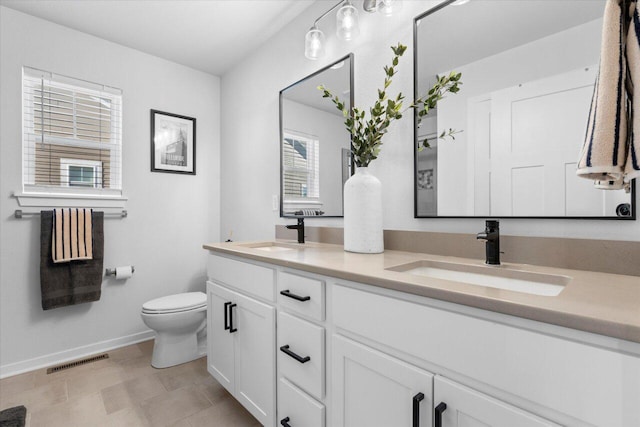 bathroom featuring toilet, double vanity, a sink, and visible vents