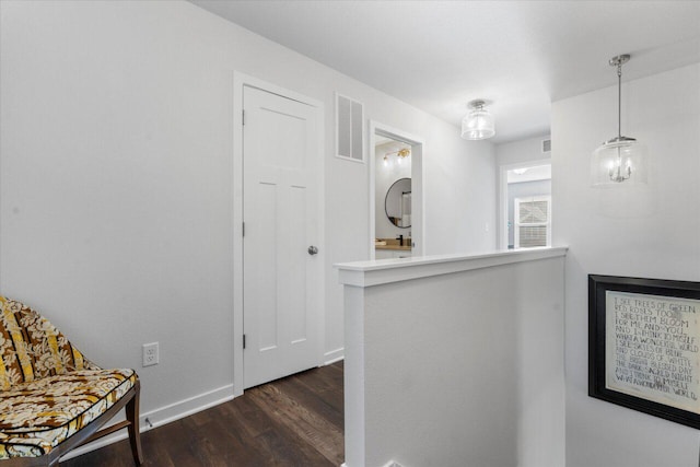 hall with dark wood finished floors, visible vents, and baseboards