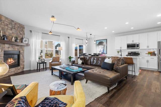 living room featuring a stone fireplace, dark wood-style flooring, and recessed lighting