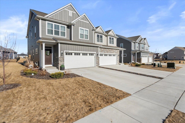 view of front of house featuring driveway, a garage, stone siding, a residential view, and board and batten siding