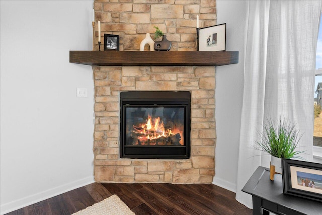 details with a stone fireplace, wood finished floors, and baseboards