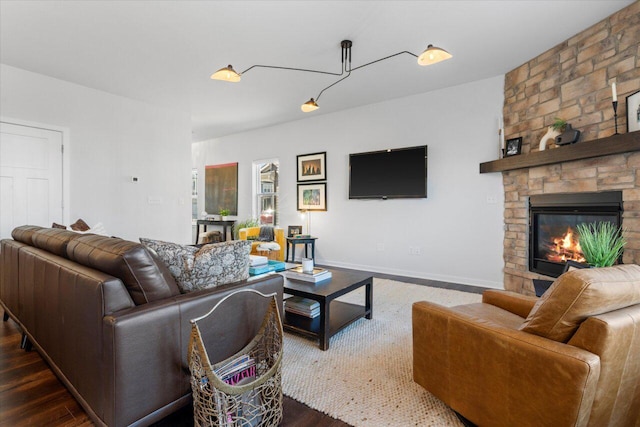 living area with a stone fireplace, wood finished floors, and baseboards