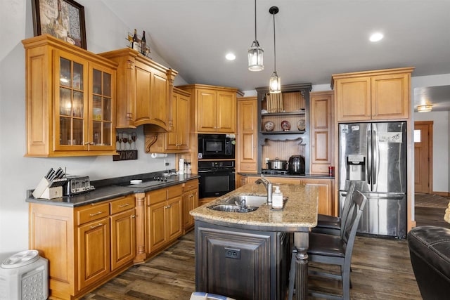 kitchen featuring glass insert cabinets, decorative light fixtures, a kitchen island with sink, black appliances, and a sink