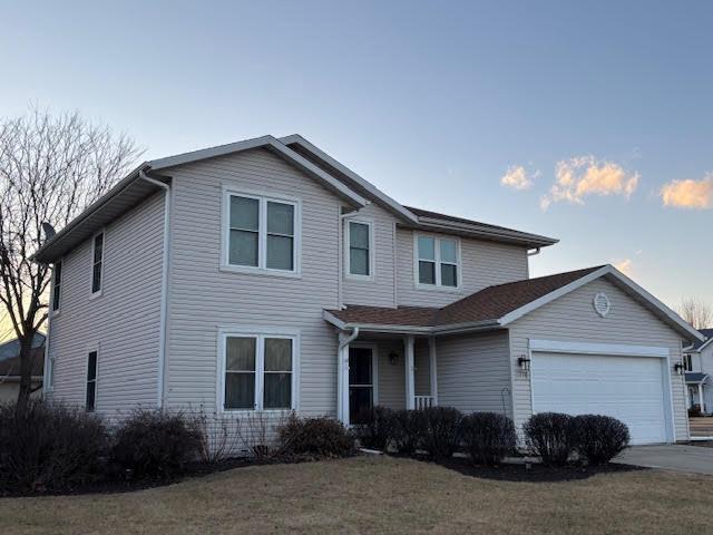 traditional-style house with a garage, concrete driveway, and a front yard