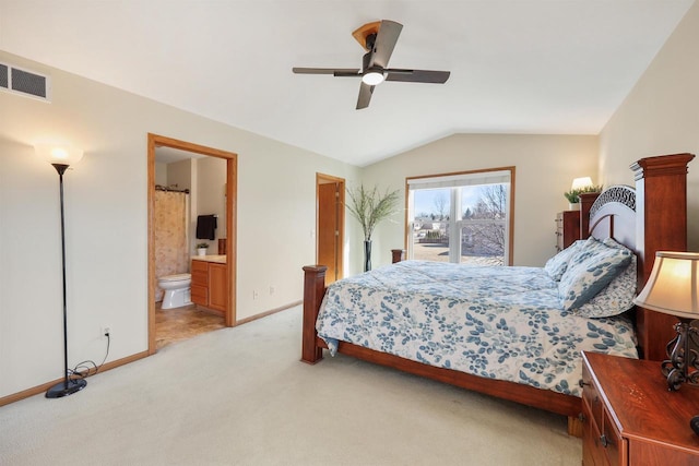 bedroom with visible vents, baseboards, lofted ceiling, light carpet, and ensuite bathroom