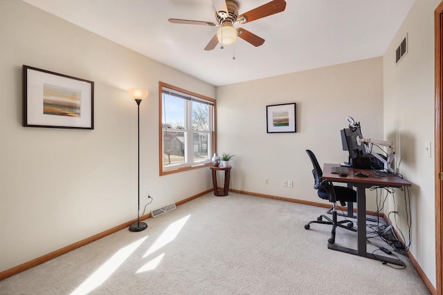 office space with visible vents, baseboards, light colored carpet, and a ceiling fan